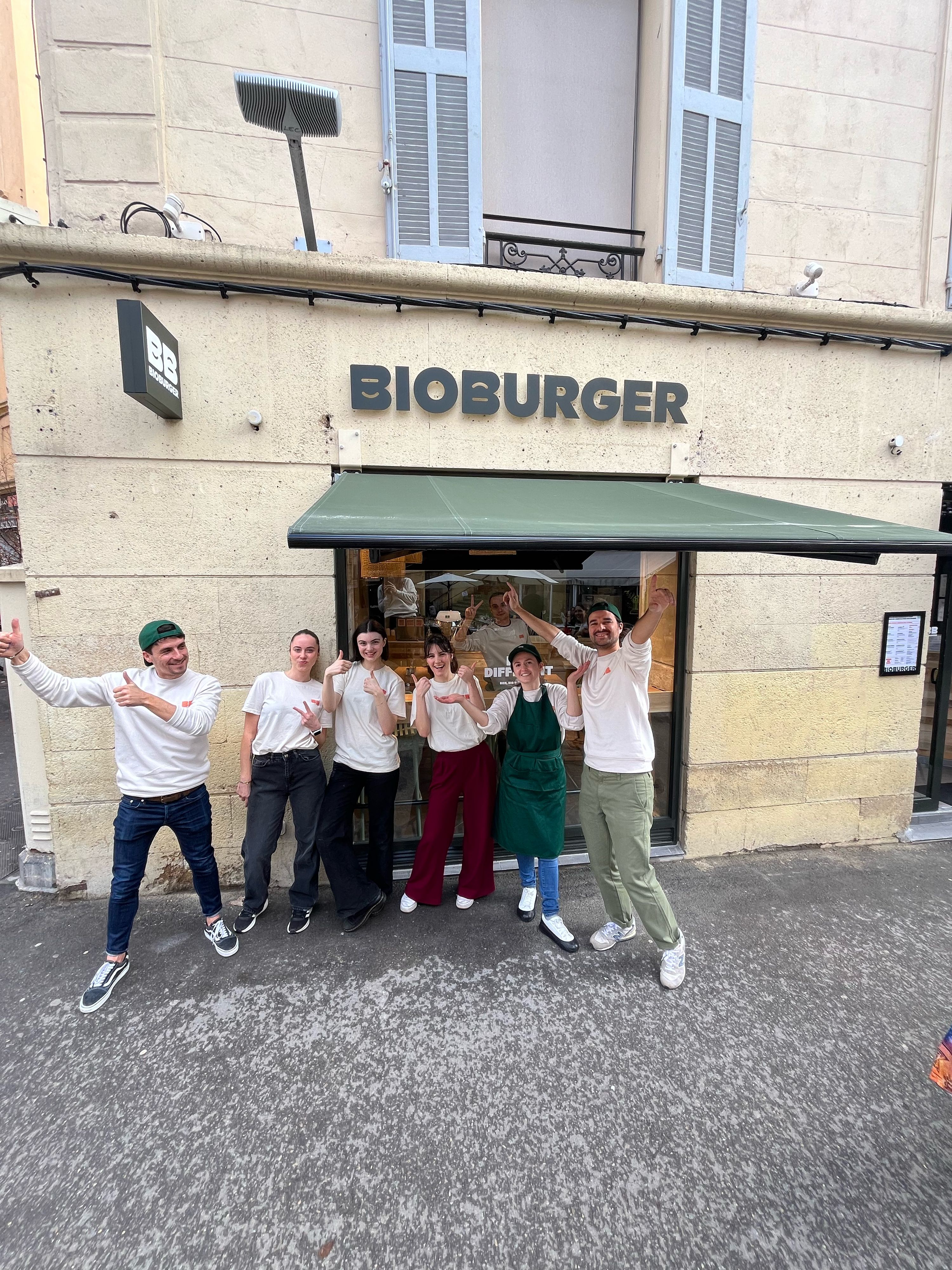 Équipe souriante devant le restaurant Bioburger Aix Mirabeau, proposant des options bio, végétariennes et véganes.