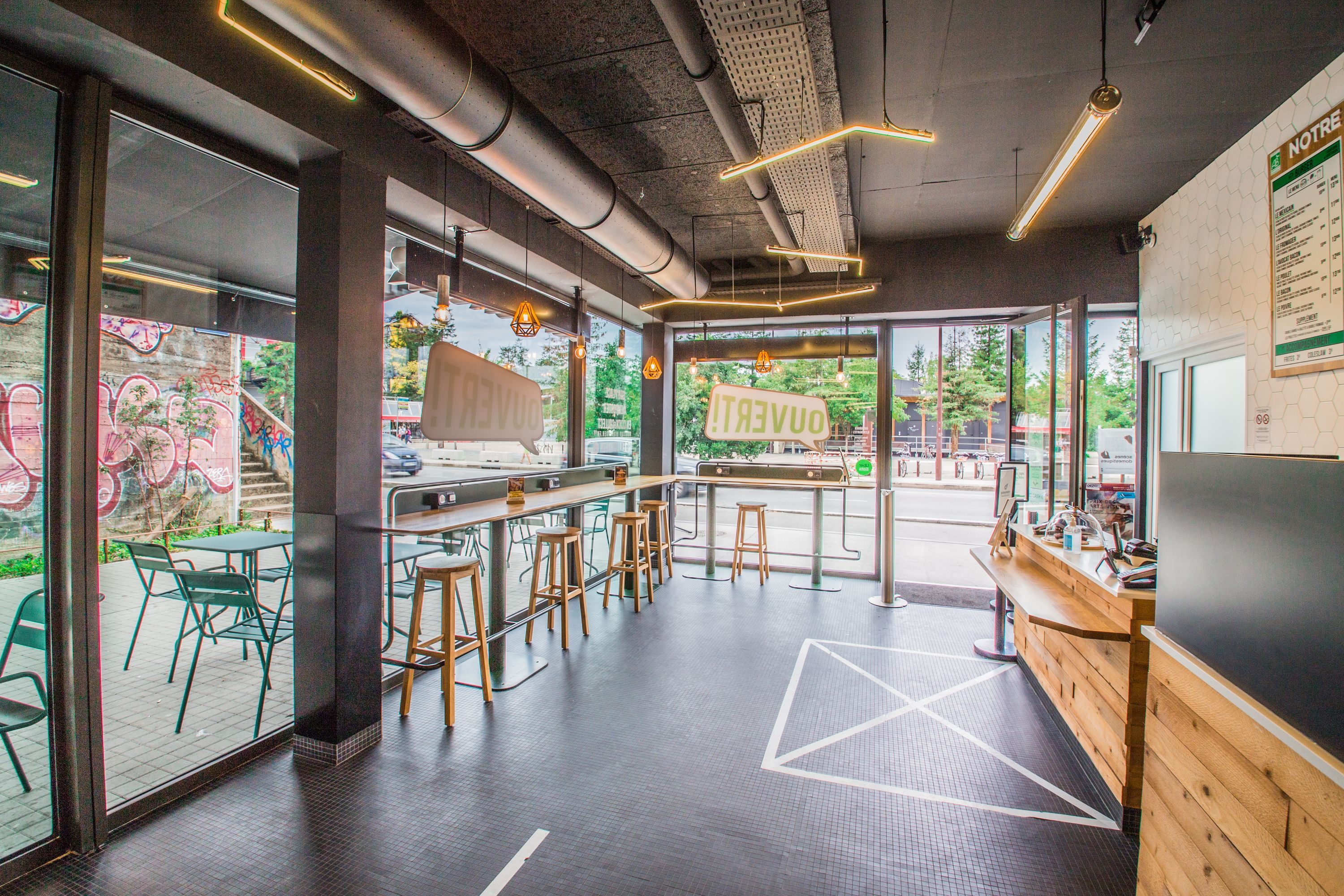 Espace intérieur lumineux avec des tables et des chaises, offrant une ambiance moderne et conviviale.
