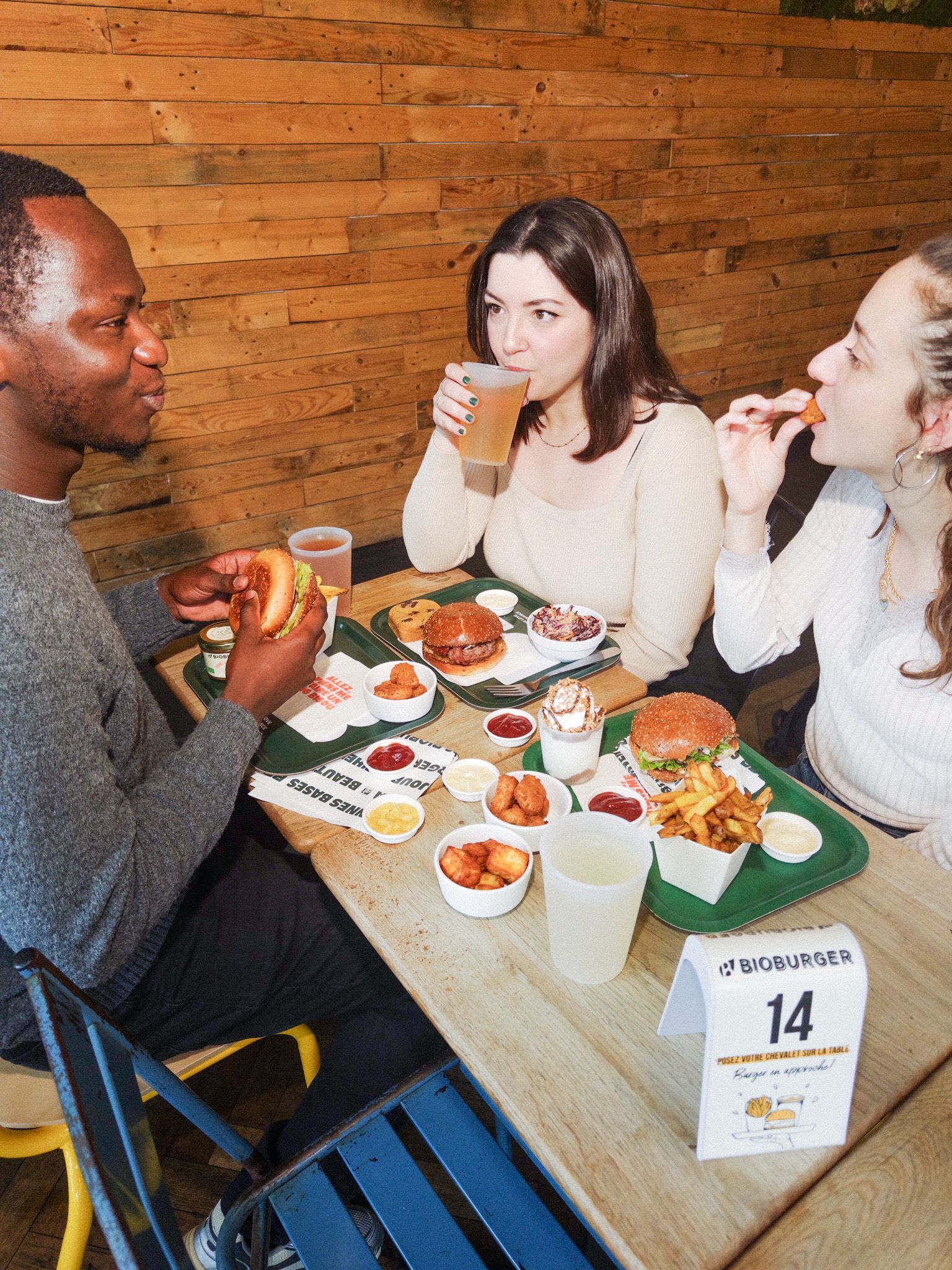 Repas convivial avec des burgers bio, végétariens et vegan, accompagné de frites et de boissons.