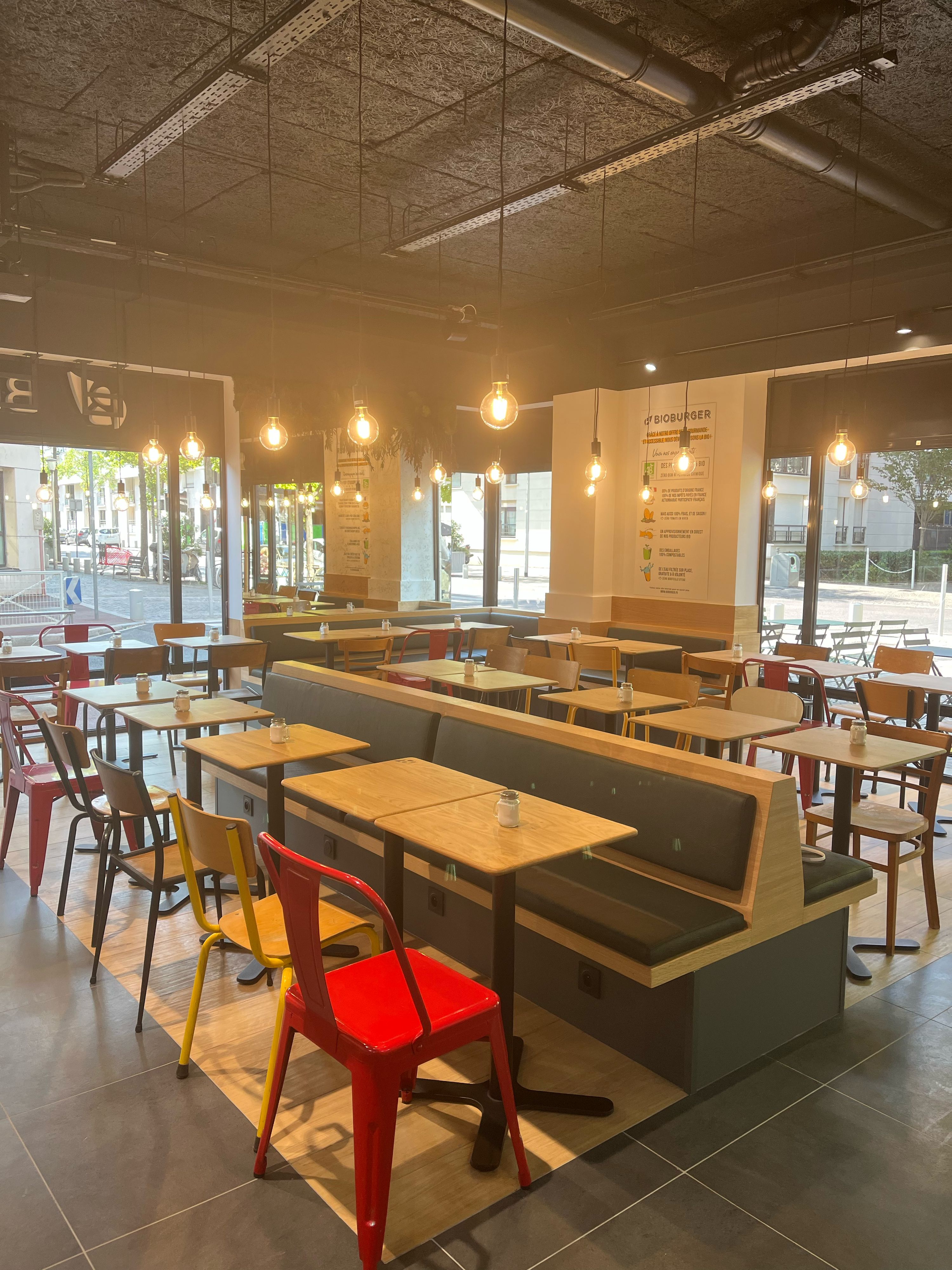 Intérieur du restaurant Bioburger avec des tables en bois et des chaises colorées, ambiance moderne.