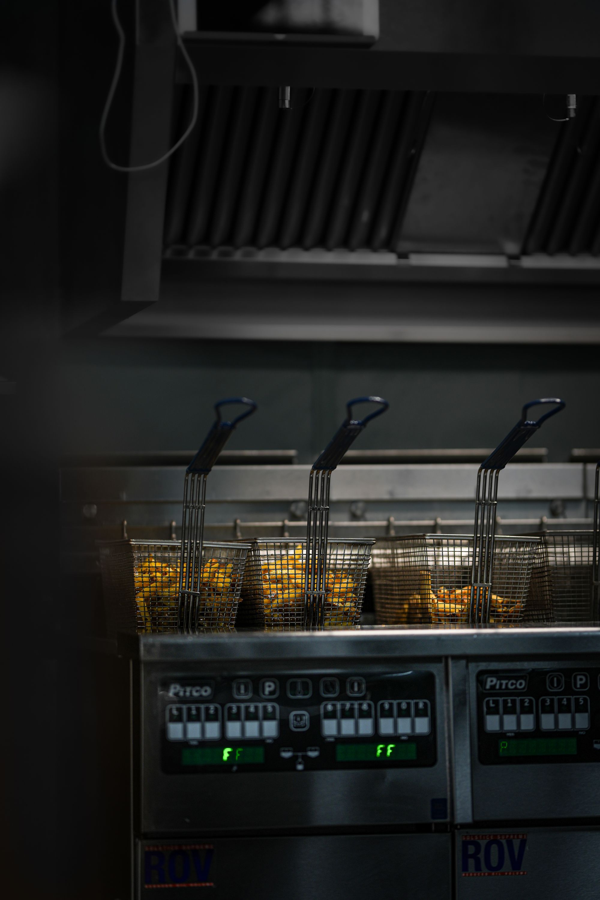 Fritures en cours avec des paniers contenant des aliments dans une friteuse industrielle.