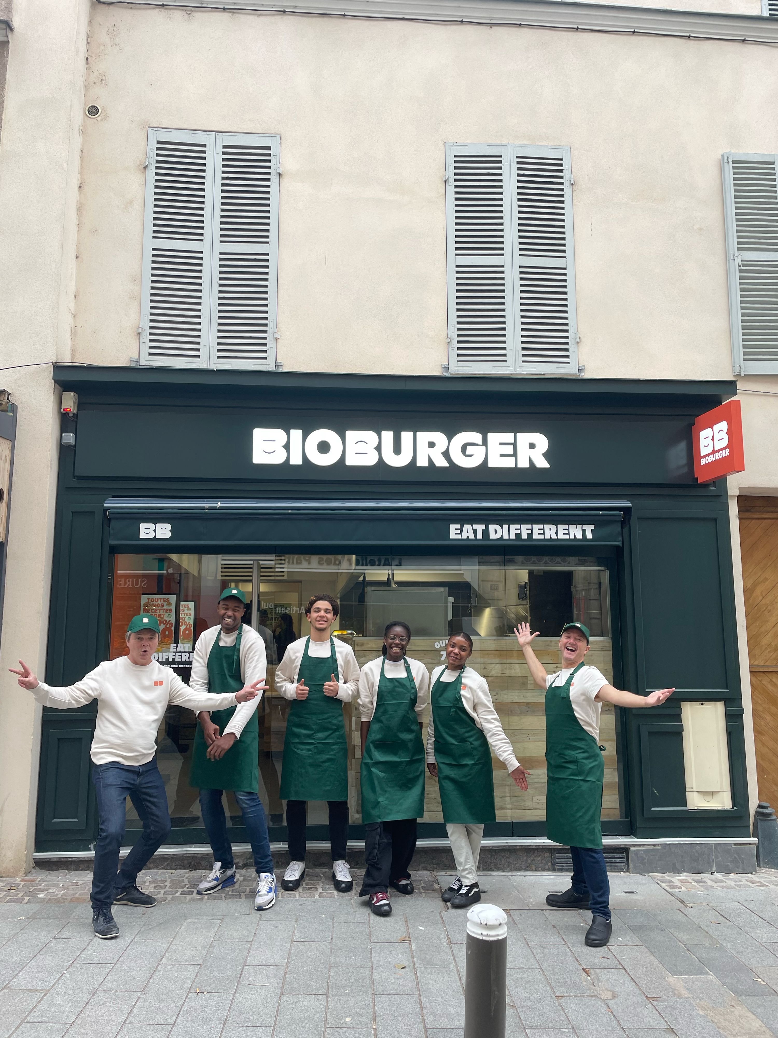 Équipe de Bioburger Suresnes Zola avec des uniformes verts, devant le restaurant mettant l'accent sur les burgers bio,