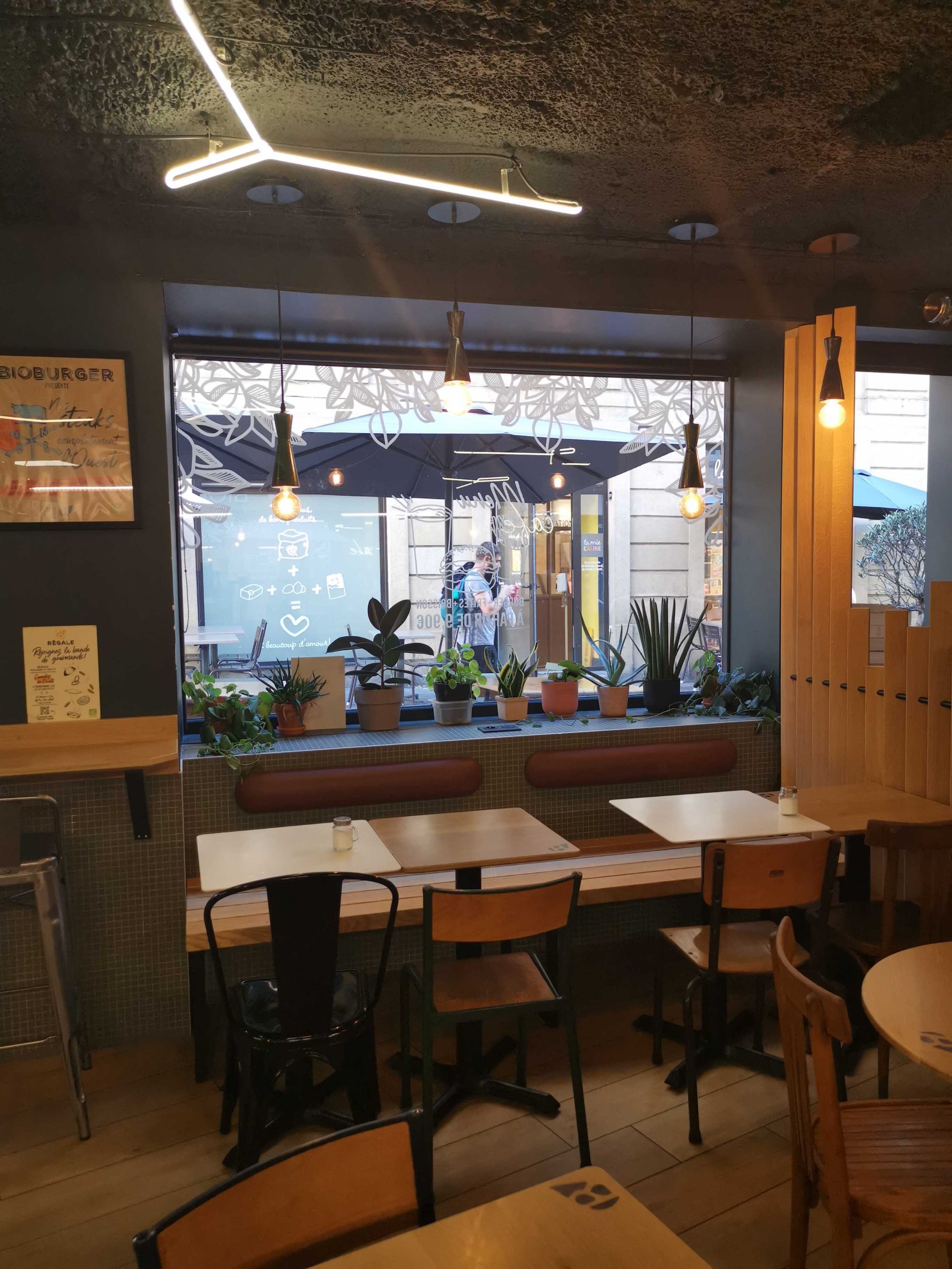 Restaurant Bioburger avec des tables en bois et des plantes, ambiance moderne et écologique.