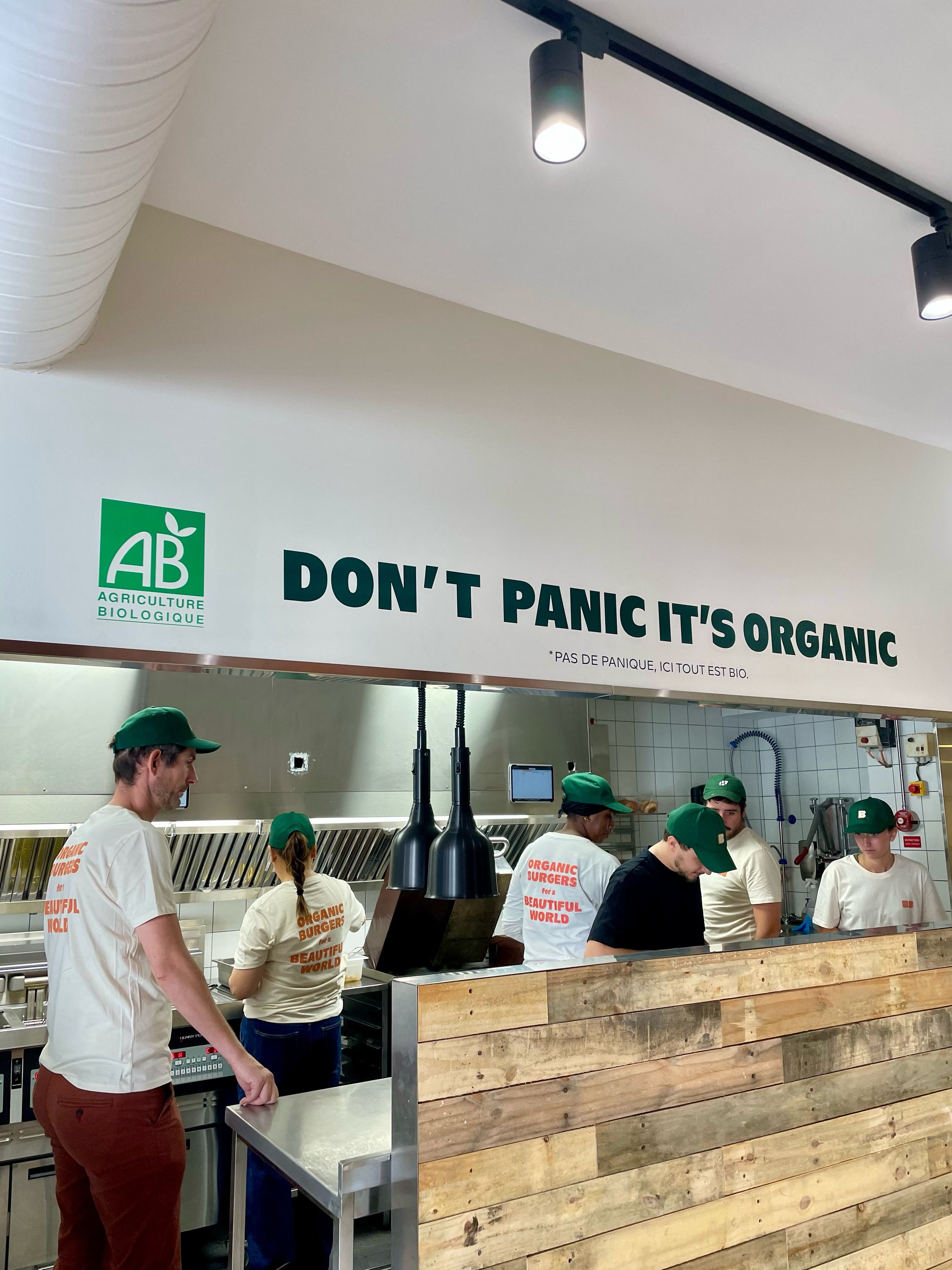 Équipe préparant des burgers bio dans un espace de cuisine avec un décor en bois.