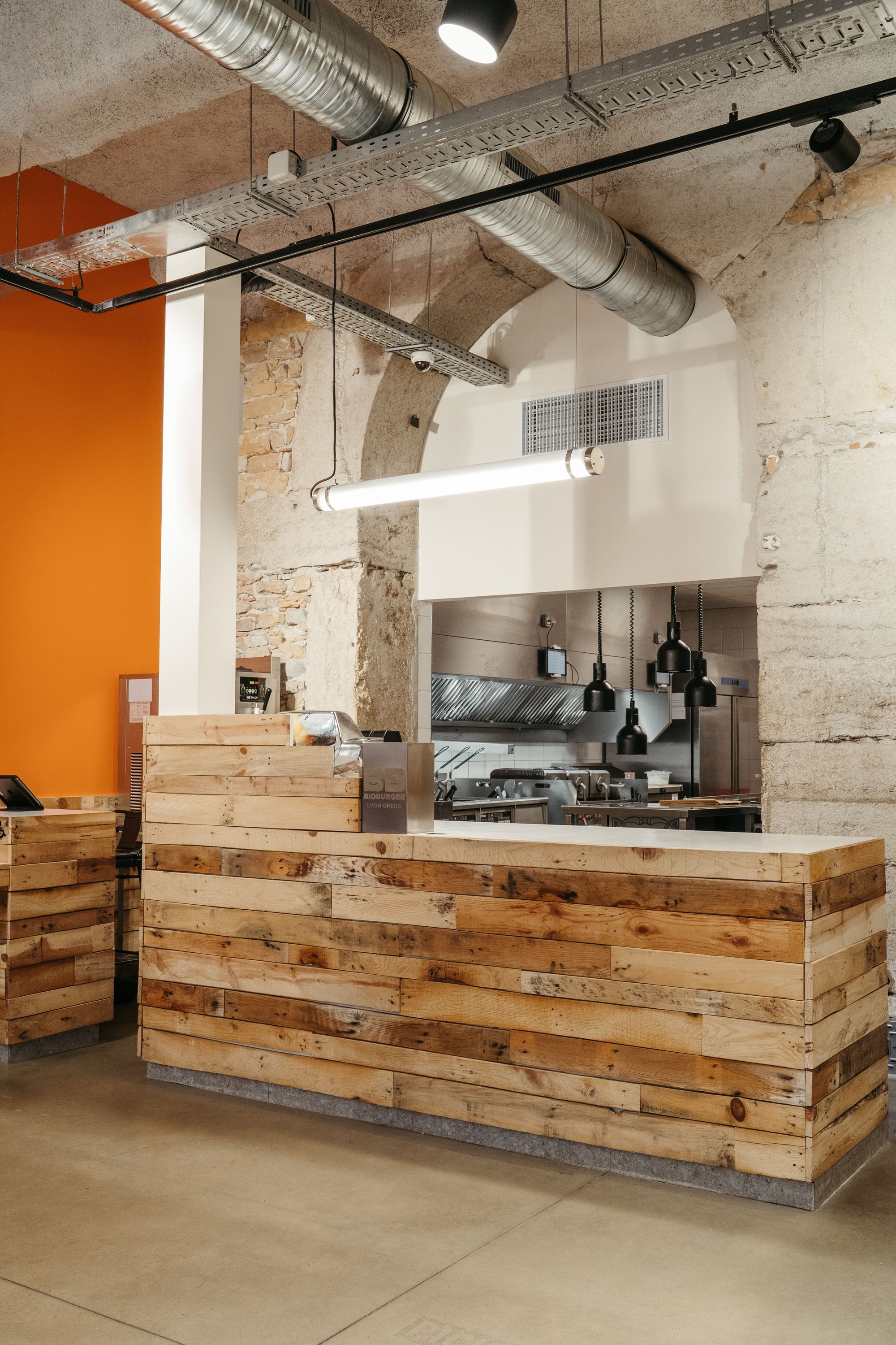 Un comptoir en bois dans un restaurant moderne, avec une cuisine ouverte à l'arrière-plan.