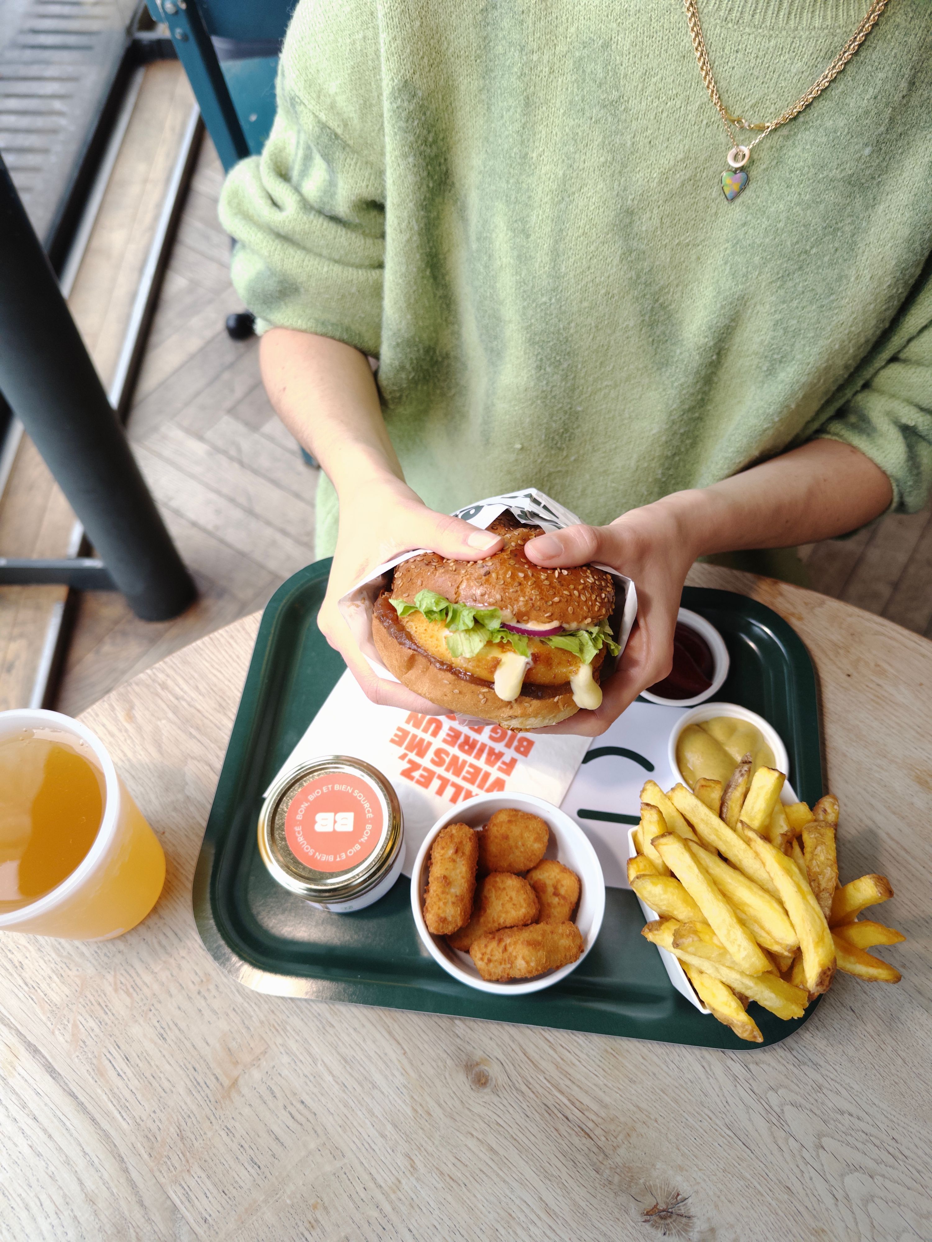 Un burger bio avec garnitures, accompagné de frites, d'une boisson et de bouchées végétariennes.