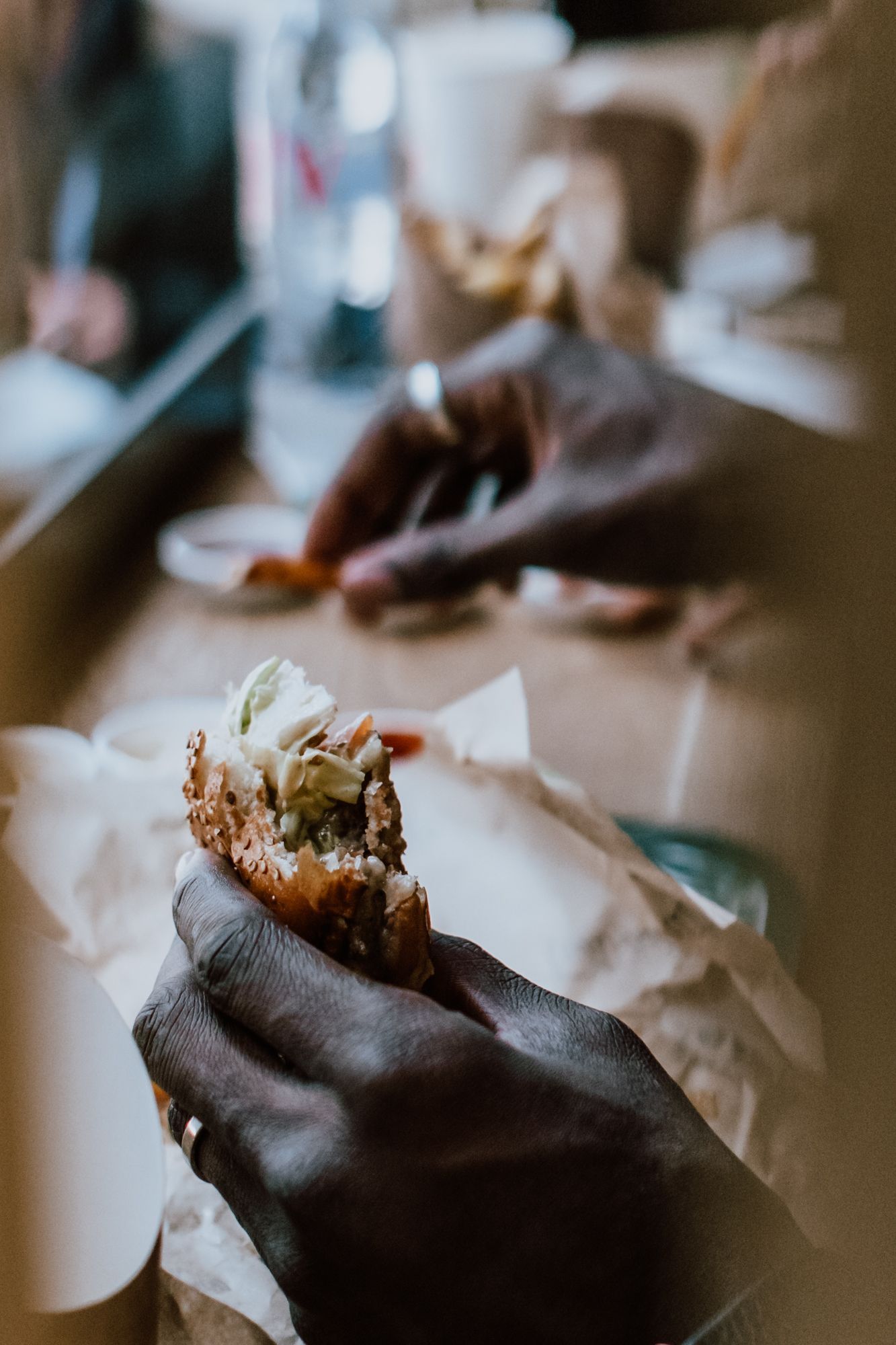 Un burger bio avec des ingrédients végétariens, tenu à la main, en arrière-plan flou.