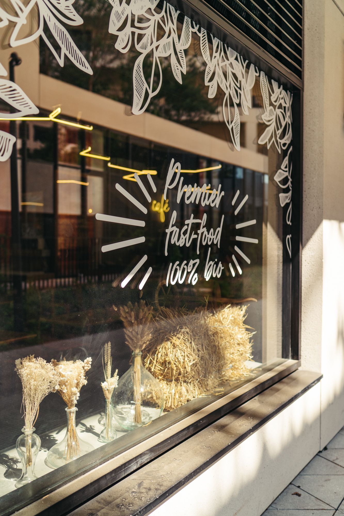 Vitrine de Bioburger Batignolles, mettant en avant des options de fast-food 100% bio avec décor végétal.