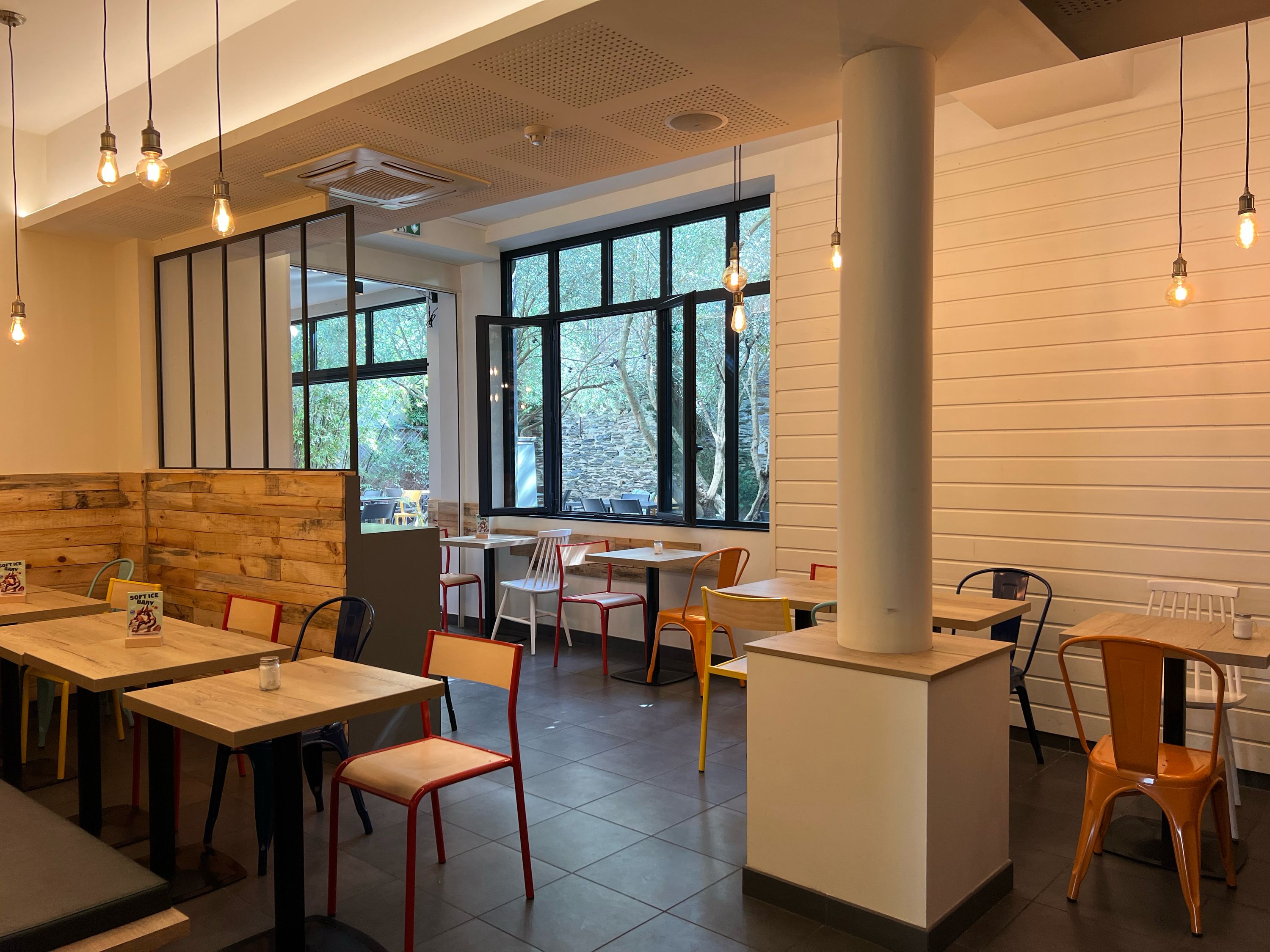 Espace de restauration moderne avec des tables et des chaises colorées, baigné de lumière naturelle.