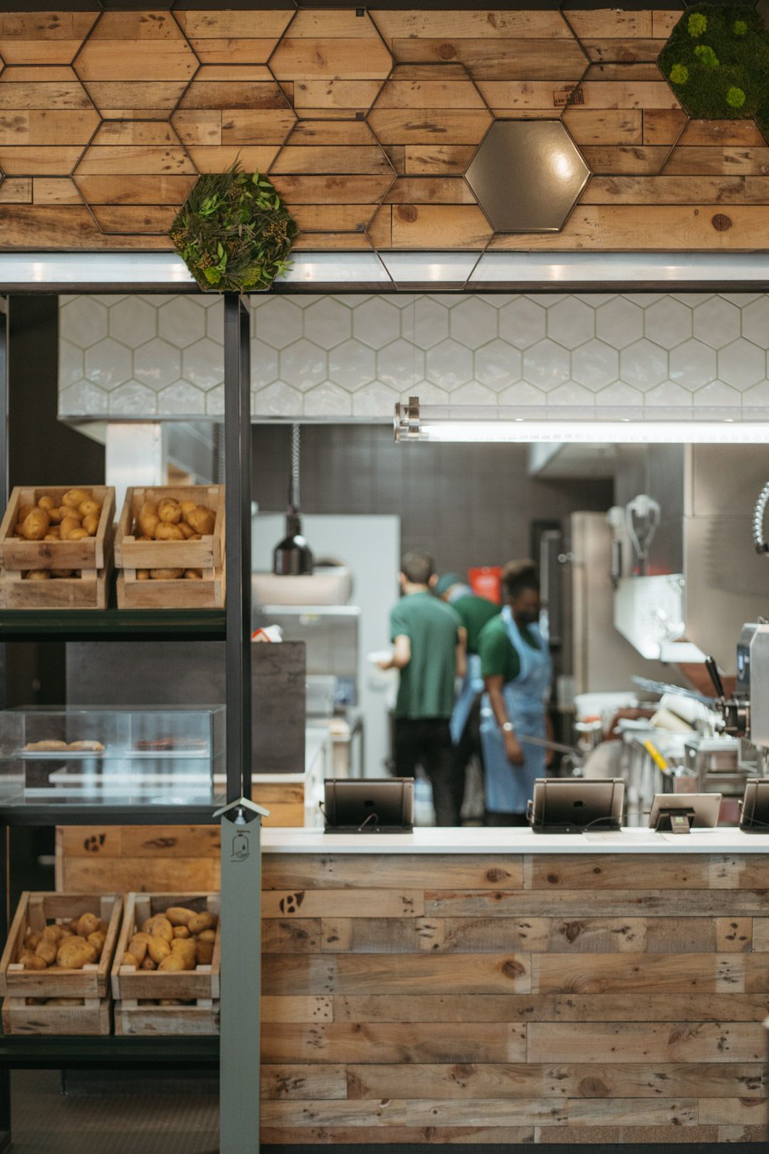 Espace de cuisine avec des murs en bois et des pommes de terre bio dans des caisses en bois, ambiance végétale.