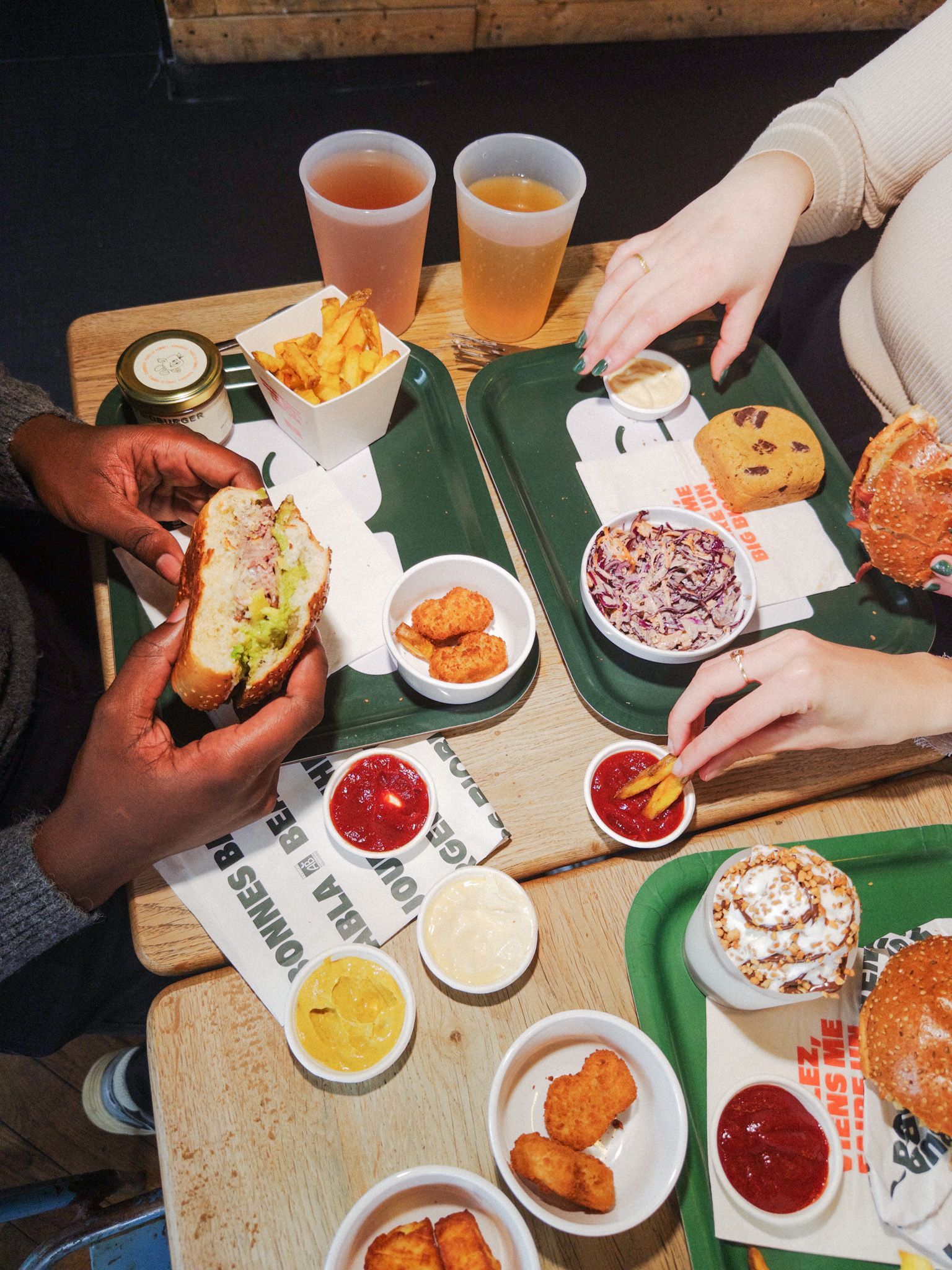 Repas végétarien avec burgers bio, frites, sauces et boissons dans un cadre décontracté.