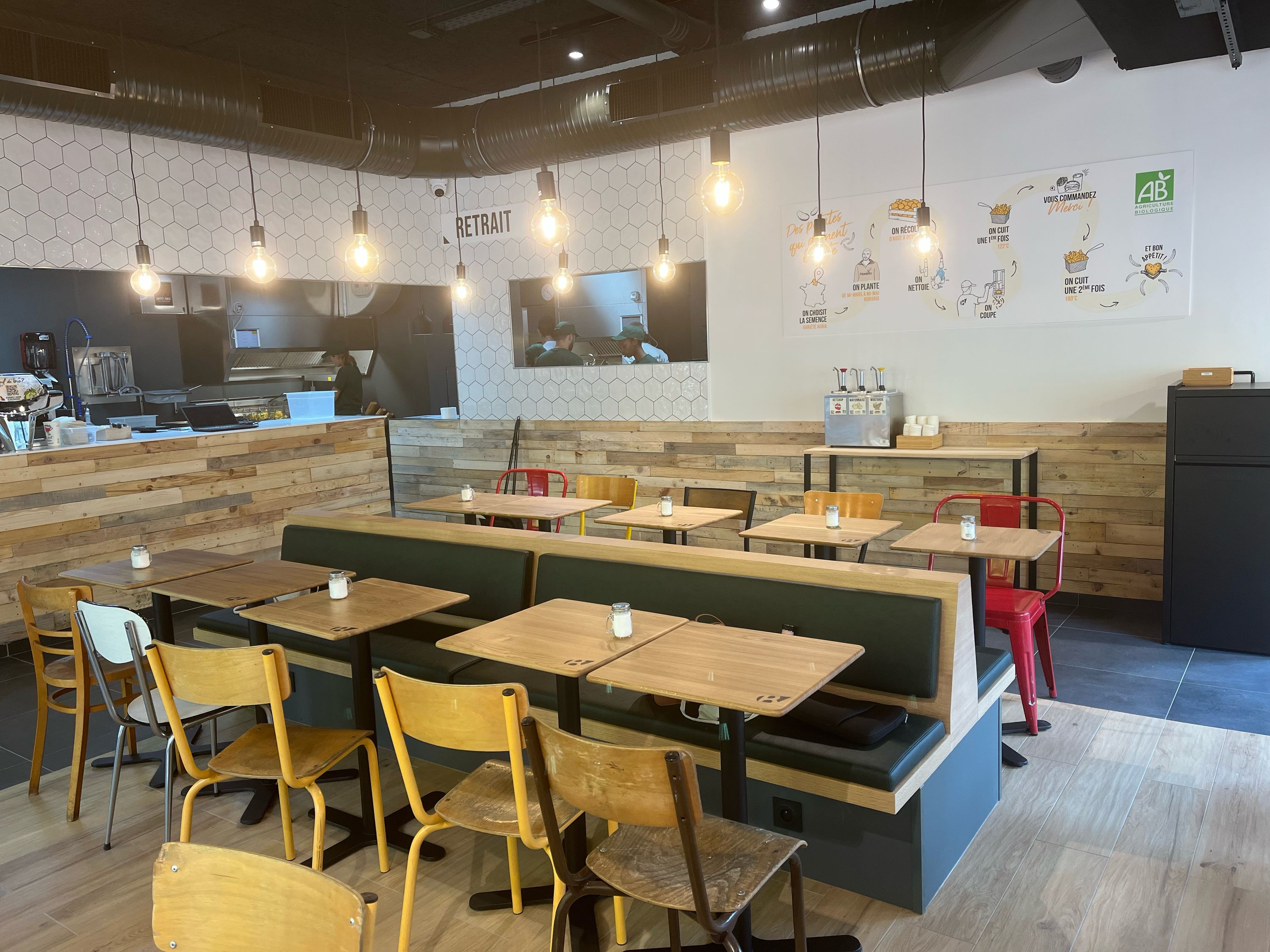 Ambiance moderne du restaurant Bioburger avec des tables et chaises en bois, offrant un cadre confortable.