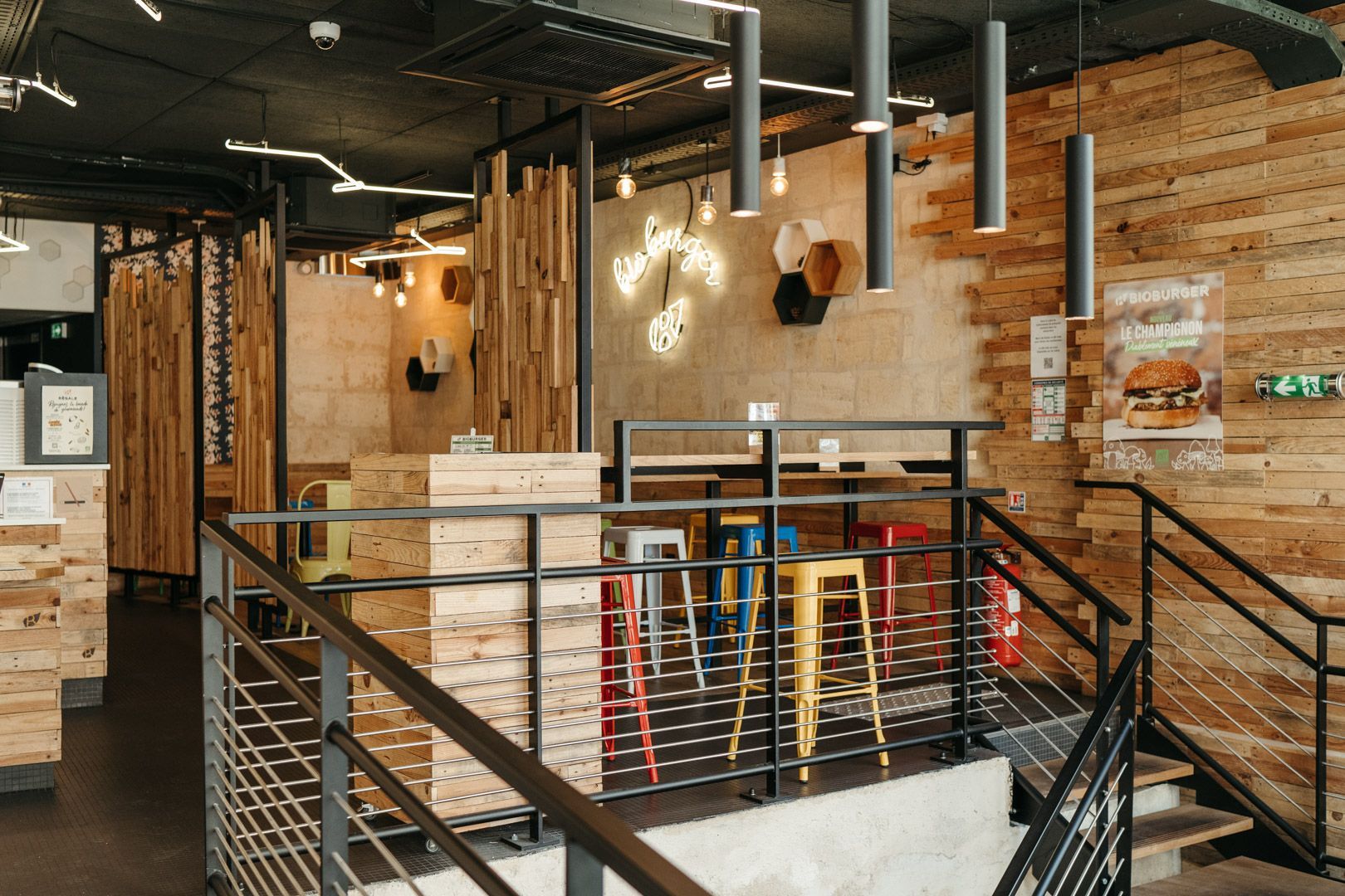 Ambiance chaleureuse du restaurant avec des éléments en bois et des sièges colorés, offrant des options Bio et Vegan.