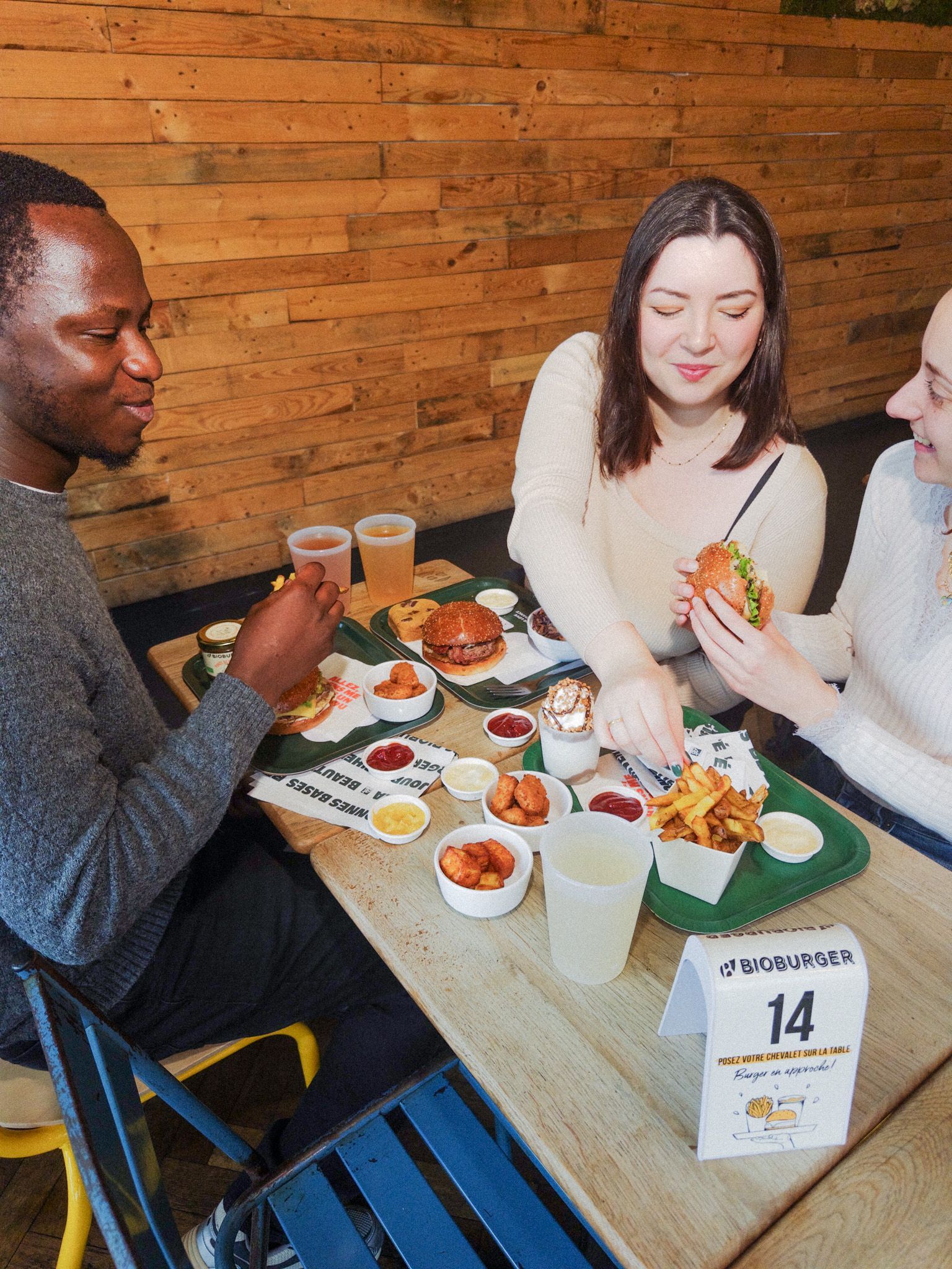 Repas partagé avec burgers bio, options végétariennes et vegan, sauces variées et frites.