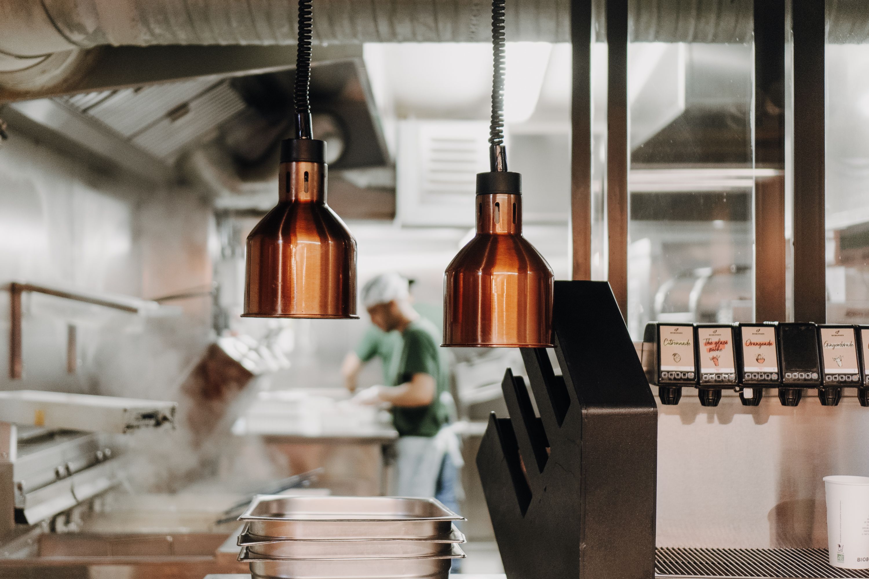 Cuisine de Bioburger Montorgueil avec des lampes suspendues et un cuisinier en arrière-plan.