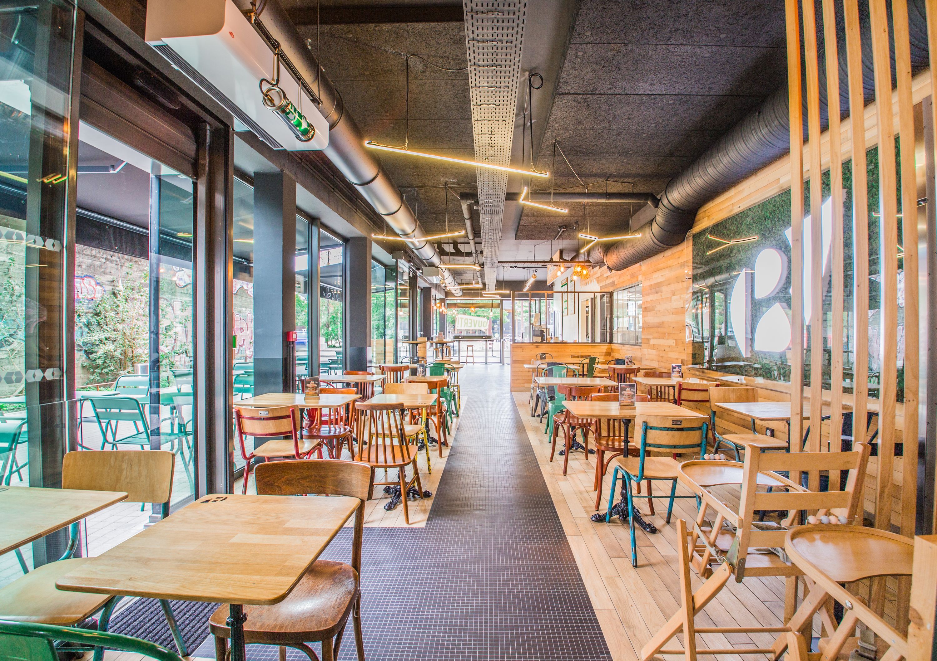 Espace de restauration moderne avec des tables en bois et des chaises colorées, ambiance conviviale.