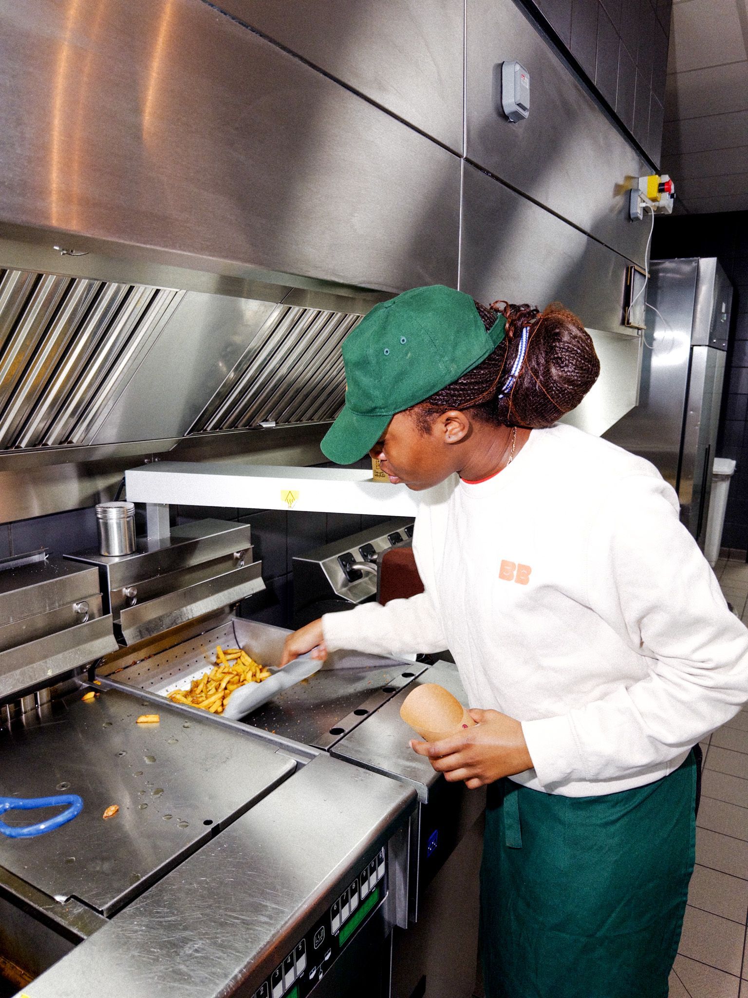 Préparation de frites dans une cuisine de restaurant, ambiance Bio, avec un employé en tenue de travail.