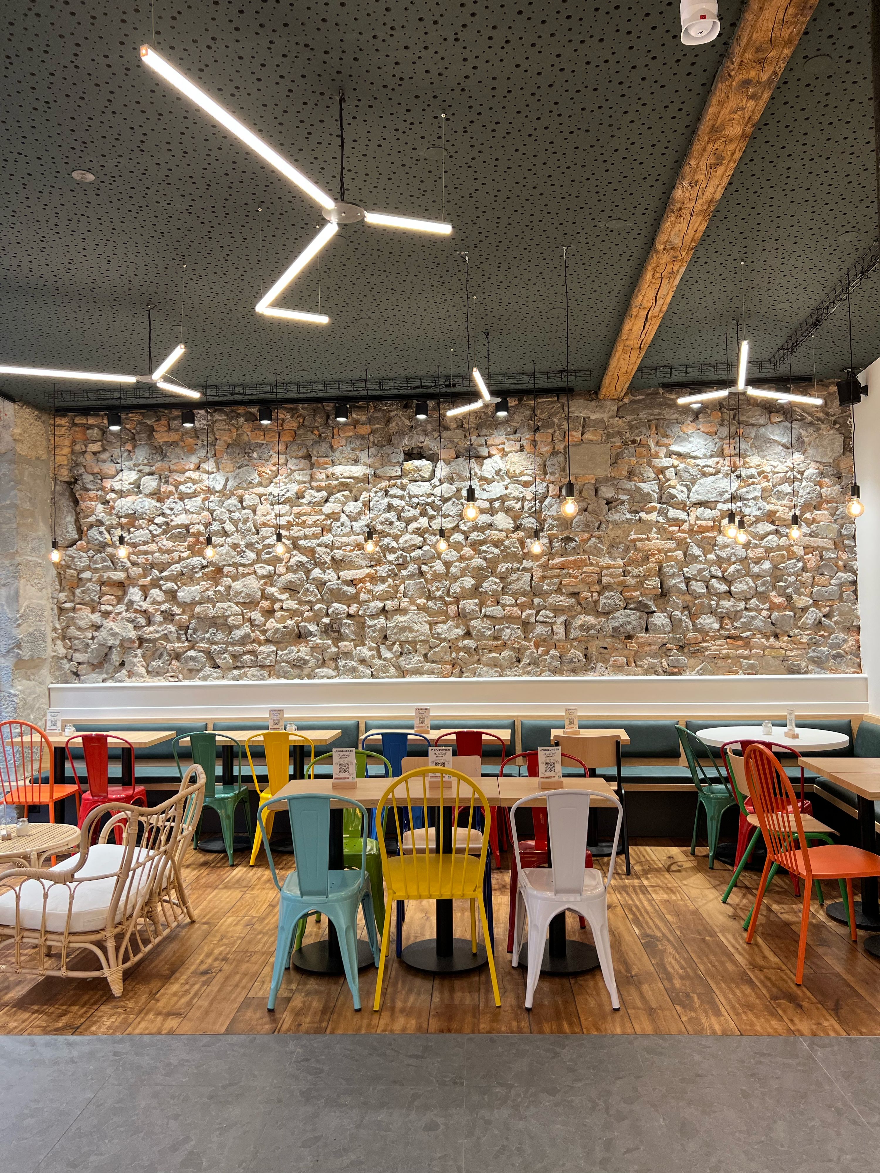 Ambiance moderne du restaurant avec des tables colorées et des murs en pierre.