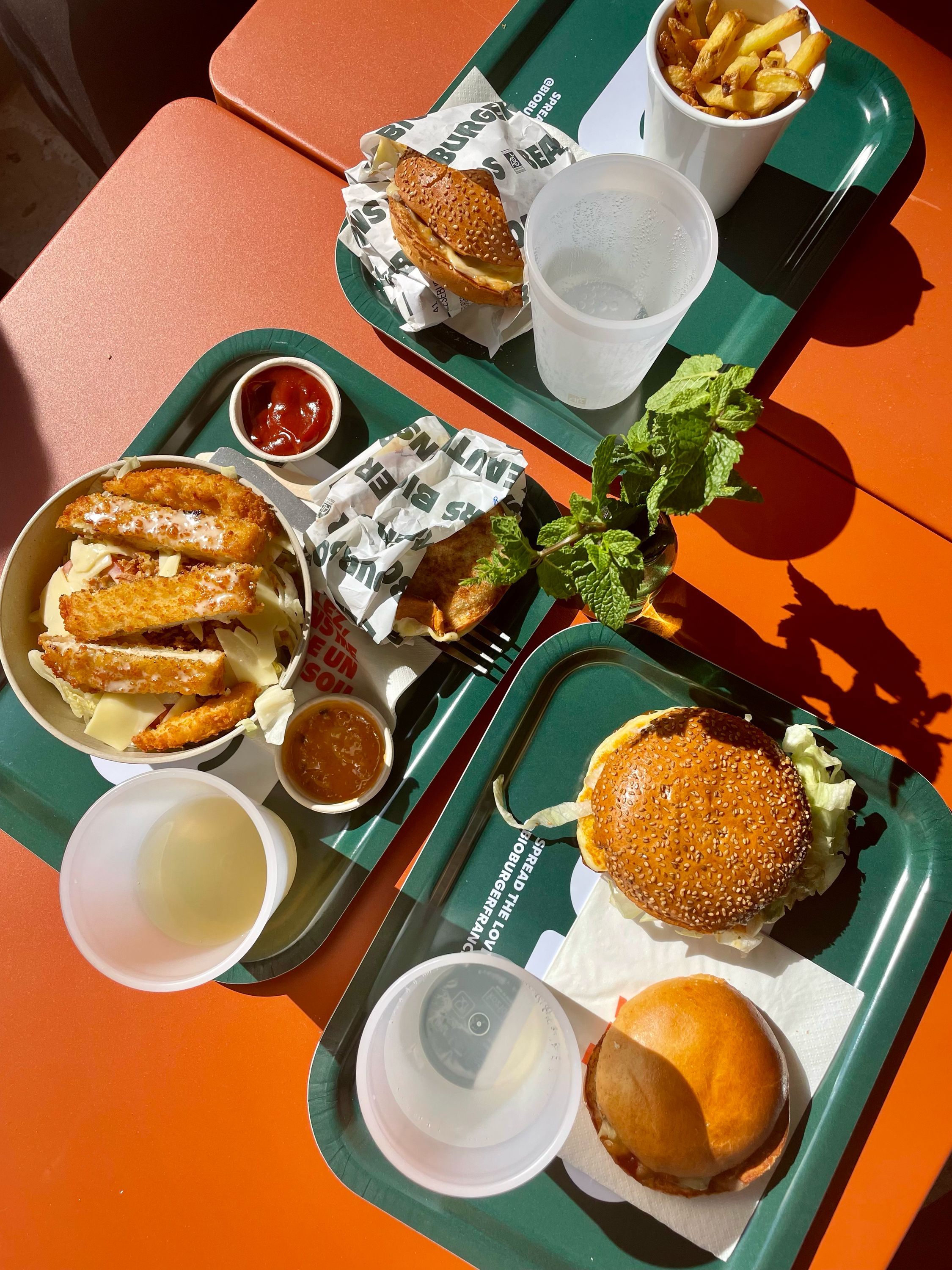 Plateaux de burgers bio, frites et boissons, avec options véganes et végétariennes.