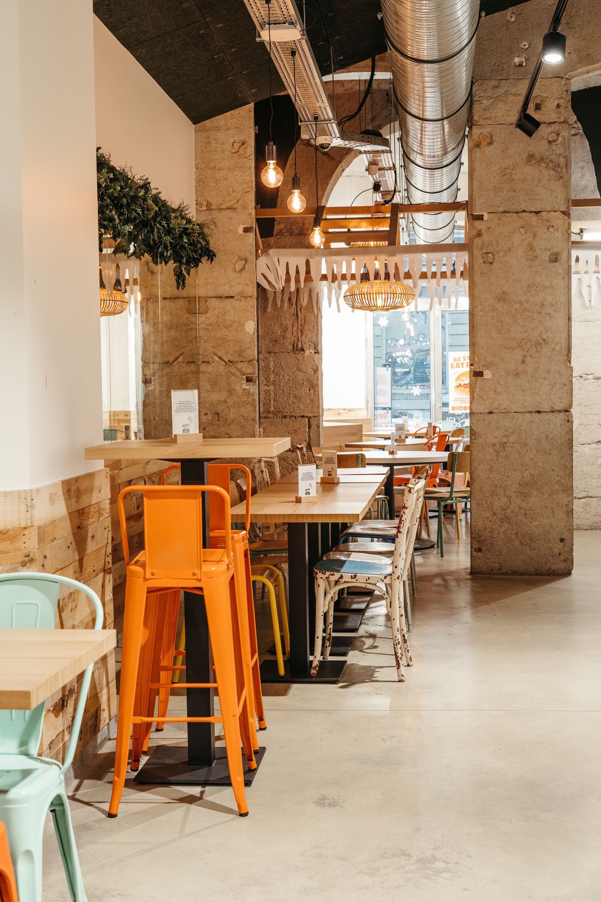 Ambiance moderne avec tables et chaises colorées, parfait pour déguster des burgers bio, végétariens ou véganes.